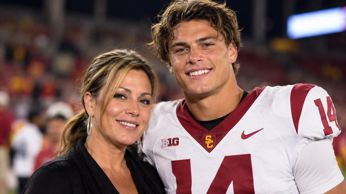 A woman posing beside a young USC football player in a stadium.